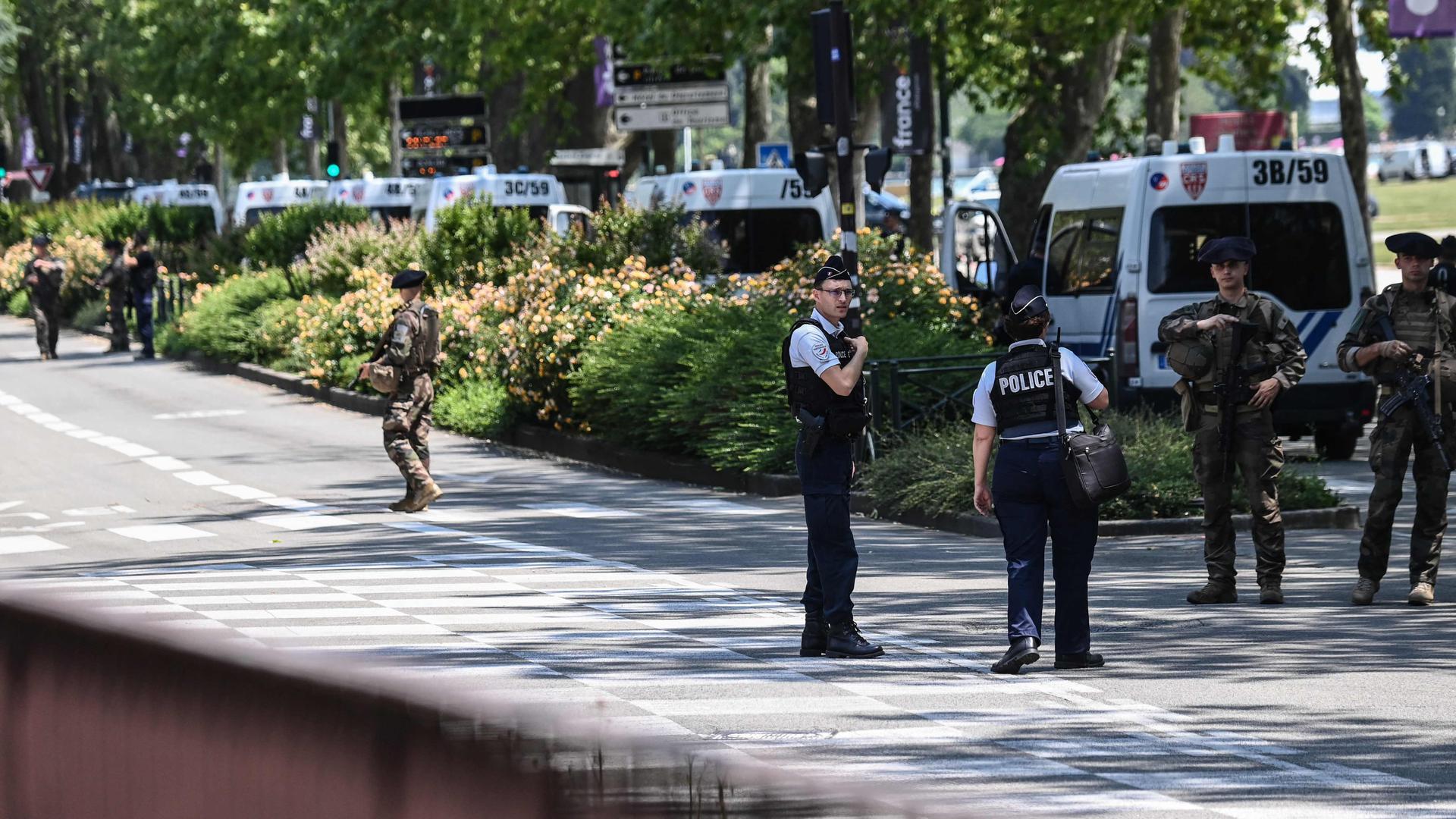 French police officers and French elite mountain infantry force 'Chasseurs Alpins' stand guard near the 'Jardins de l'Europe' in Annecy, central-eastern France on June 8, 2023, following a mass stabbing in the French Alpine town. Seven people, including six children, have been injured in a mass stabbing in the town of Annecy in the French Alps, security sources told AFP. A man armed with a knife attacked a group of children aged around three years old as they played in a park near the lake in the town at around 9:45 am (0745 GMT), a security source who asked not to be named and a local official told AFP. (Photo by OLIVIER CHASSIGNOLE / AFP)