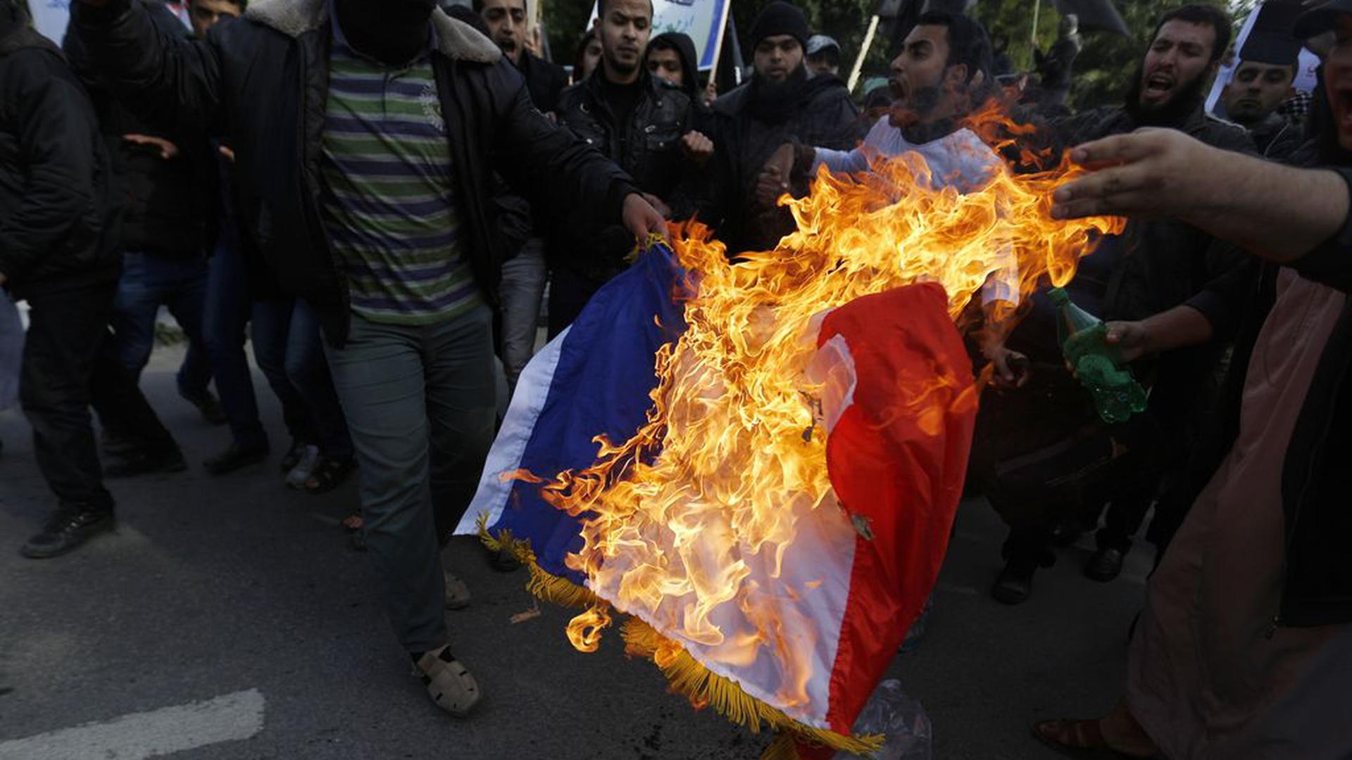 TOPSHOTS
A Palestinian Salafist burns a French national flag during a protest against the printing of satirical sketches of the Prophet Mohammed by French satirical weekly Charlie Hebdo on January 19, 2015 on their way to the French Cultural Centre in Gaza city. The walls of Gaza's French Cultural Center were painted on January 16 with graffitti in reaction to a cartoon published in the latest issue of Charlie Hebdo showing on its cover the prophet Mohammed holding a "Je Suis Charlie" (I am Charlie) sign under the headline "All is forgiven".  AFP PHOTO / MOHAMMED ABED
