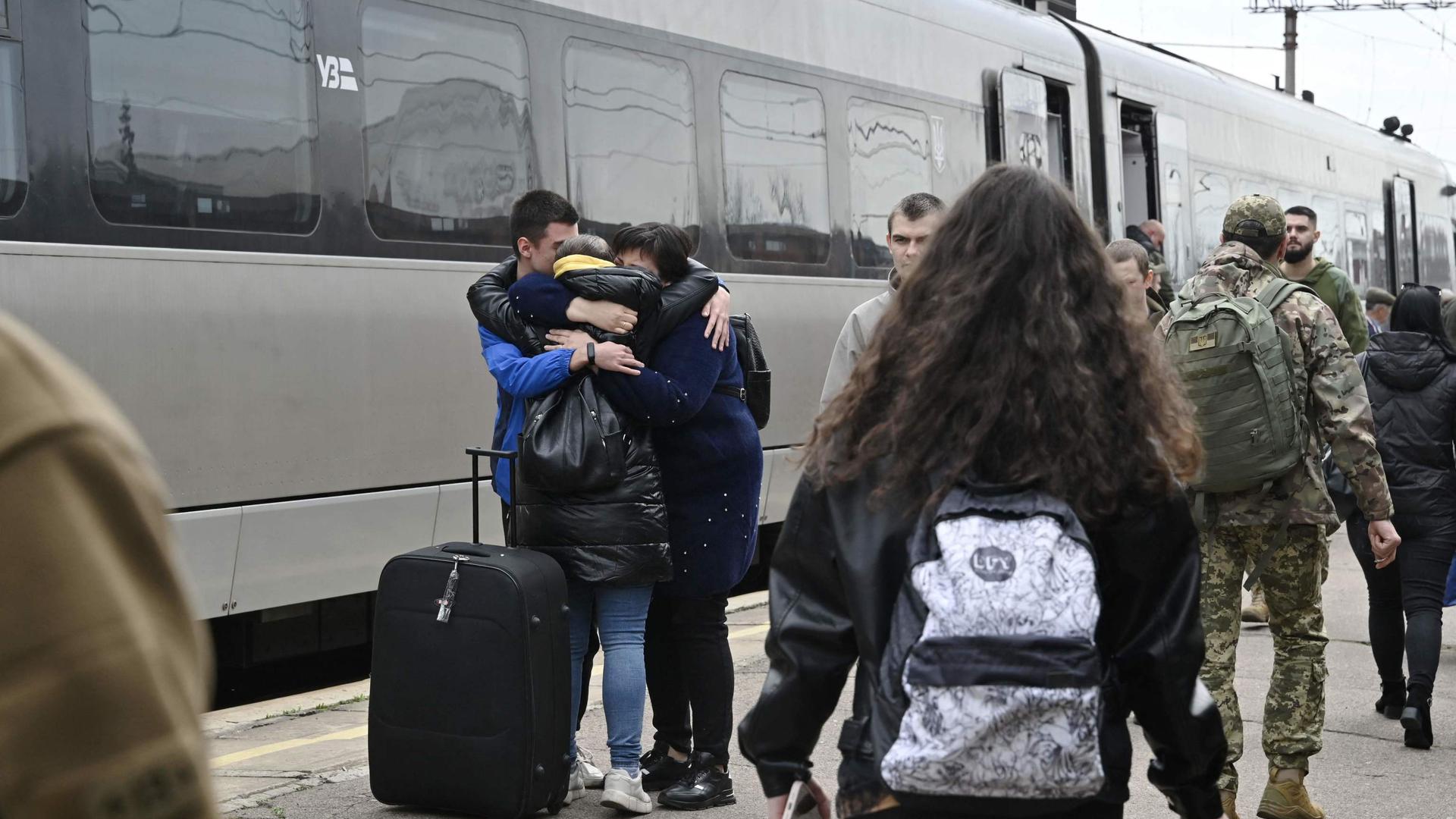 Passengers hug on a platform next to a train arriving from Kyiv at the train station in Kramatorsk, in the Donetsk region on April 8, 2023, amid the Russian invasion on Ukraine. - Ukrainians in the eastern city of Kramatorsk on April 8 laid flowers at a small memorial at the central train station one year after Russian missiles hit the transport hub killing dozens. The strikes on April 8, 2022, killed 61 people and injured more than 160 bystanders in one of the single deadliest attacks of the war that targeted civilians fleeing Russia's advance. (Photo by Genya SAVILOV / AFP)