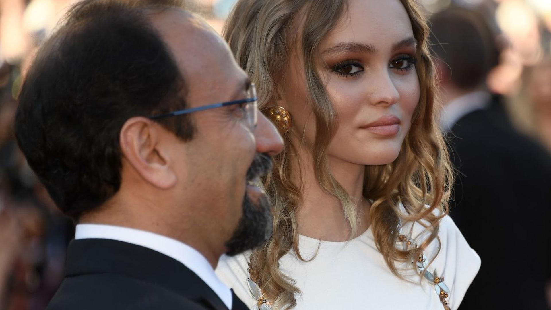 Lily-Rose Depp (R) and Iranian director Asghar Farhadi pose as they arrive on May 17, 2017 for the screening of the film 'Ismael's Ghosts' (Les Fantomes d'Ismael) during the opening ceremony of the 70th edition of the Cannes Film Festival in Cannes, southern France.  / AFP PHOTO / Anne-Christine POUJOULAT