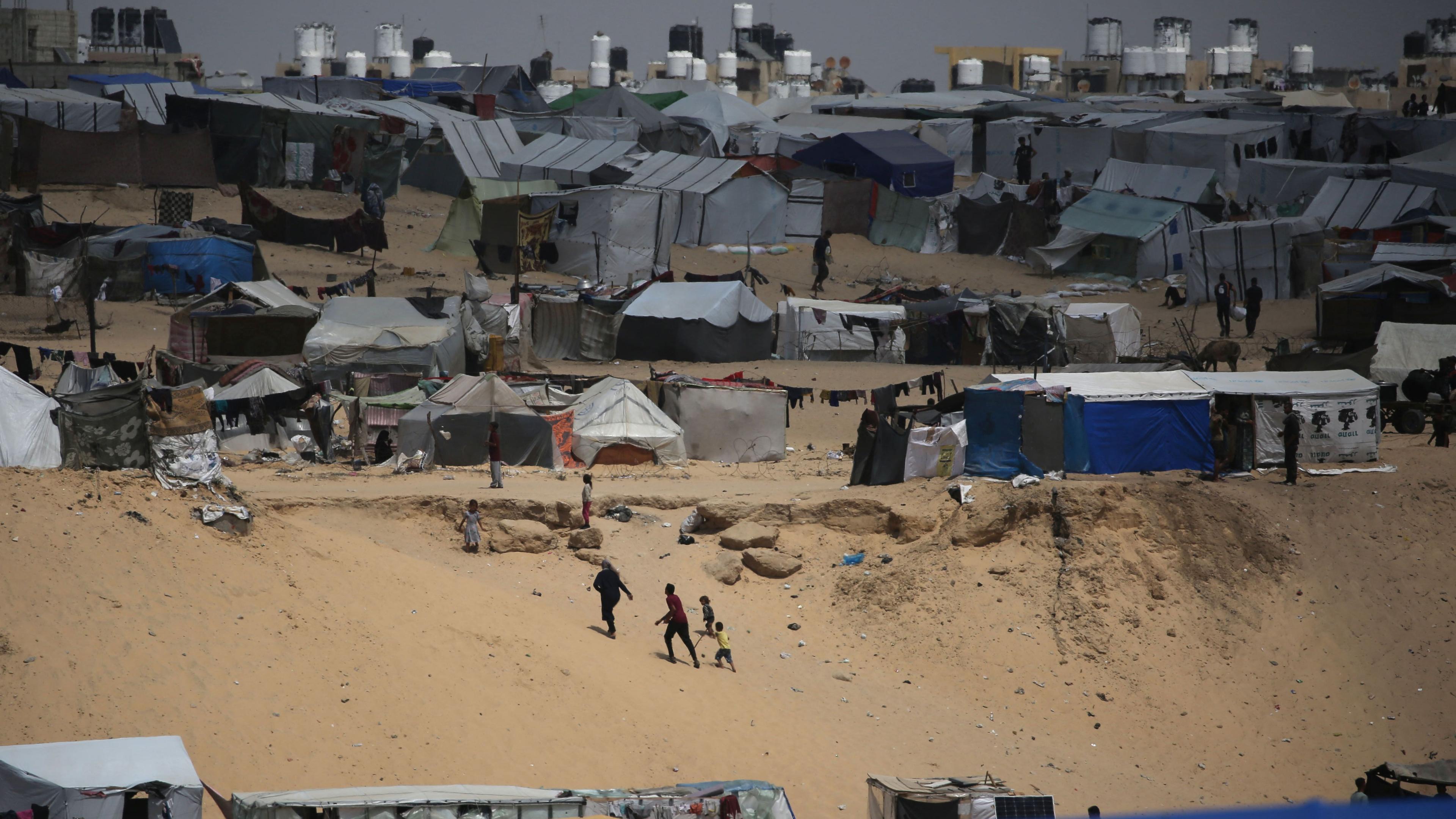 TOPSHOT - Palestinians walk in a camp for displaced people in Rafah in the southern Gaza Strip by the border with Egypt on April 28, 2024, amid the ongoing conflict between Israel and the Palestinian militant group Hamas. (Photo by AFP)