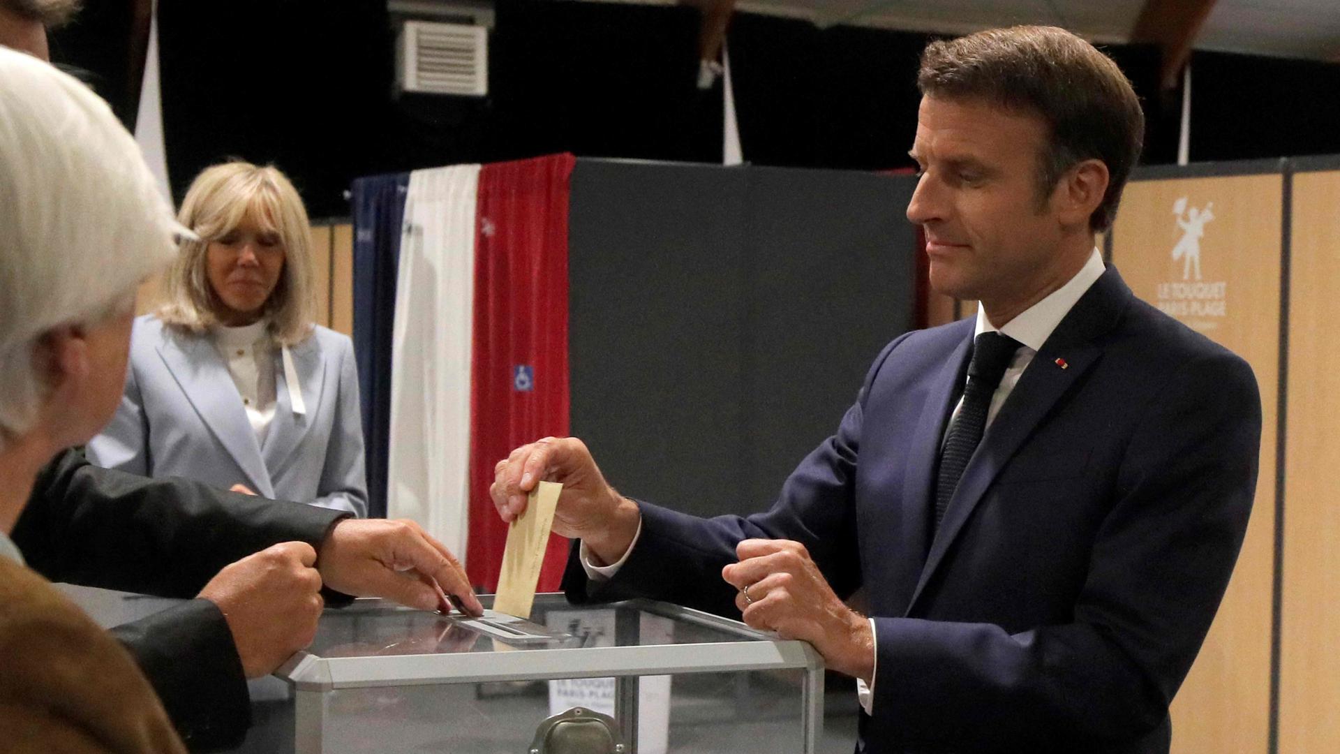 France's President Emmanuel Macron casts his ballot next to his wife Brigitte Macron during the second stage of French parliamentary elections at a polling station in Le Touquet, northern France on June 19, 2022. (Photo by Michel Spingler / POOL / AFP)