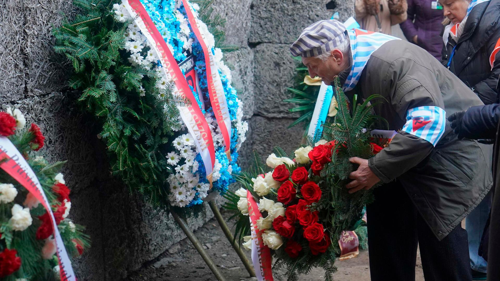 Ein Holocaust-Überlebender legt an der Todeswand in Auschwitz einen Blumenkranz nieder. 