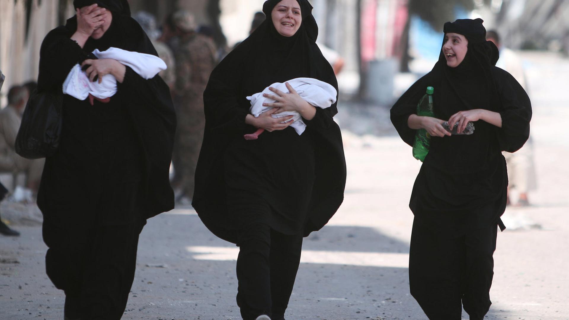 Des femmes portent leurs bébés, le visage découvert, après avoir été libérées des griffes de l'EI, dans la région d'Alep.