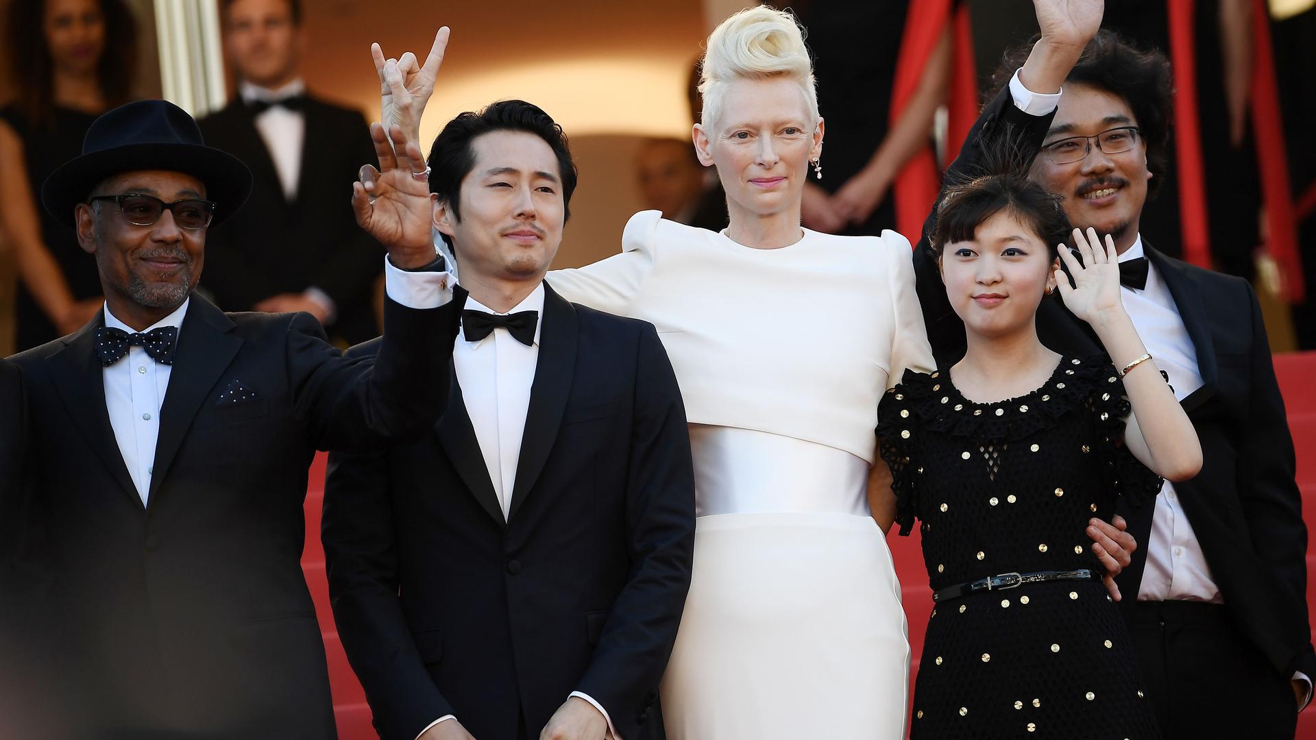 (From L) Danish-born actor Giancarlo Esposito, US-South Korean actor Steven Yeun, British actress Tilda Swinton, South Korean actress Ahn Seo-hyun and South Korean director Bong Joon-ho wave as they arrive on May 19, 2017 for the screening of the film 'Okja' at the 70th edition of the Cannes Film Festival in Cannes, southern France.  / AFP PHOTO / Anne-Christine POUJOULAT