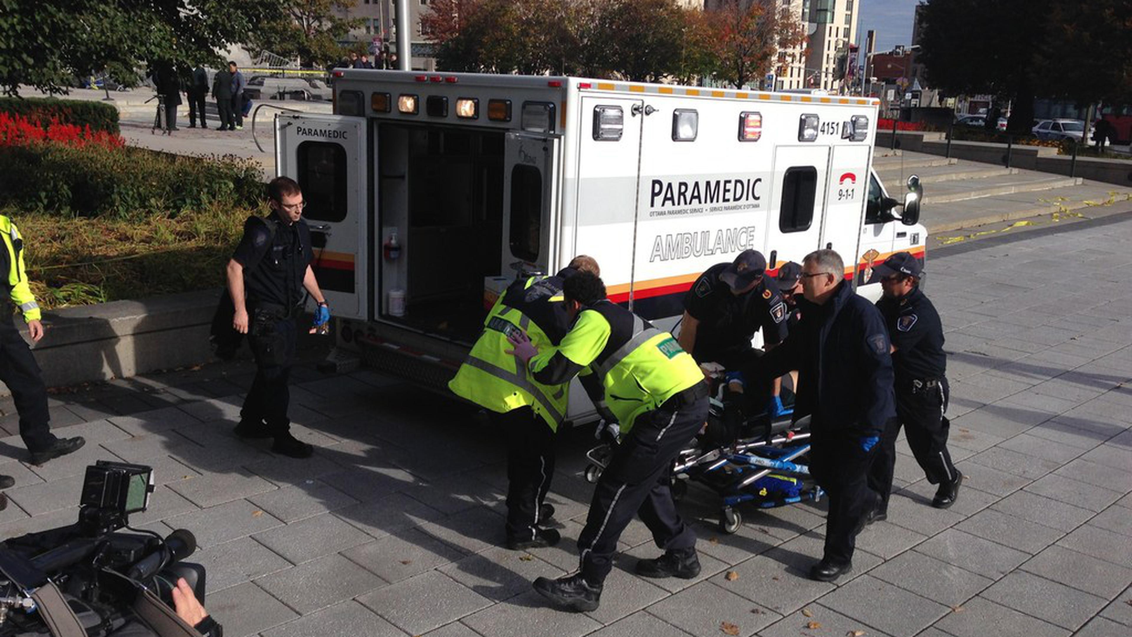 Police and paramedics transport a wounded Canadian soldier on October 22, 2014 in Ottawa, Ontario. Canadian police backed by armored vehicles surrounded parliament in Ottawa on Wednesday after a soldier was shot while guarding a nearby monument. Witnesses said they saw a gunman running to the parliament building after the shooting. Heavily armed police raced to seal off the building and the office of Canadian Prime Minister Stephen Harper. AFP PHOTO/MICHEL COMTE