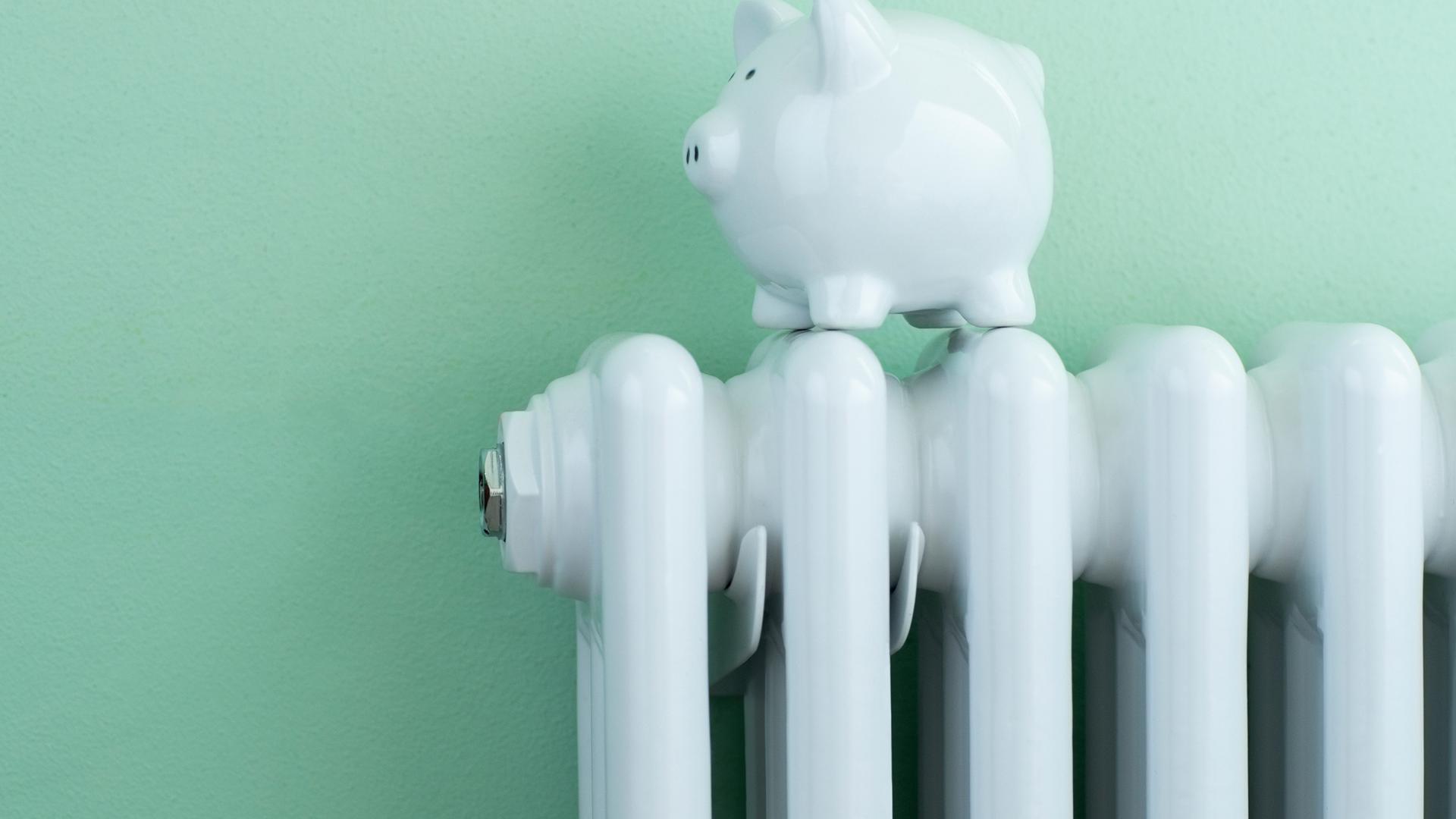 Piggy Bank Balanced On Radiator To Illustrate Energy Costs