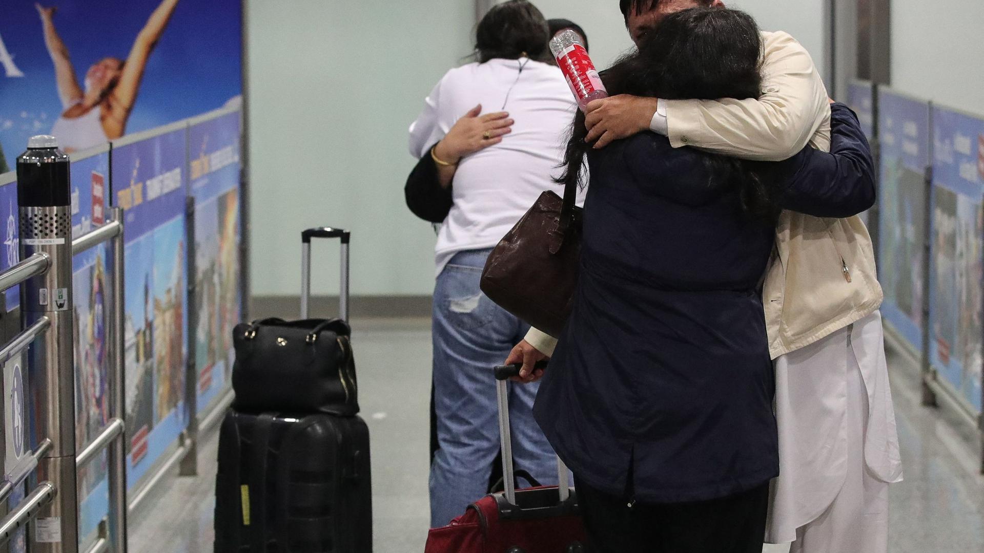 People among the first evacuees from Kabul, hug as they arrive at Frankfurt International Airport in western Germany in the early hours of August 18, 2021. (Photo by Armando BABANI / AFP)