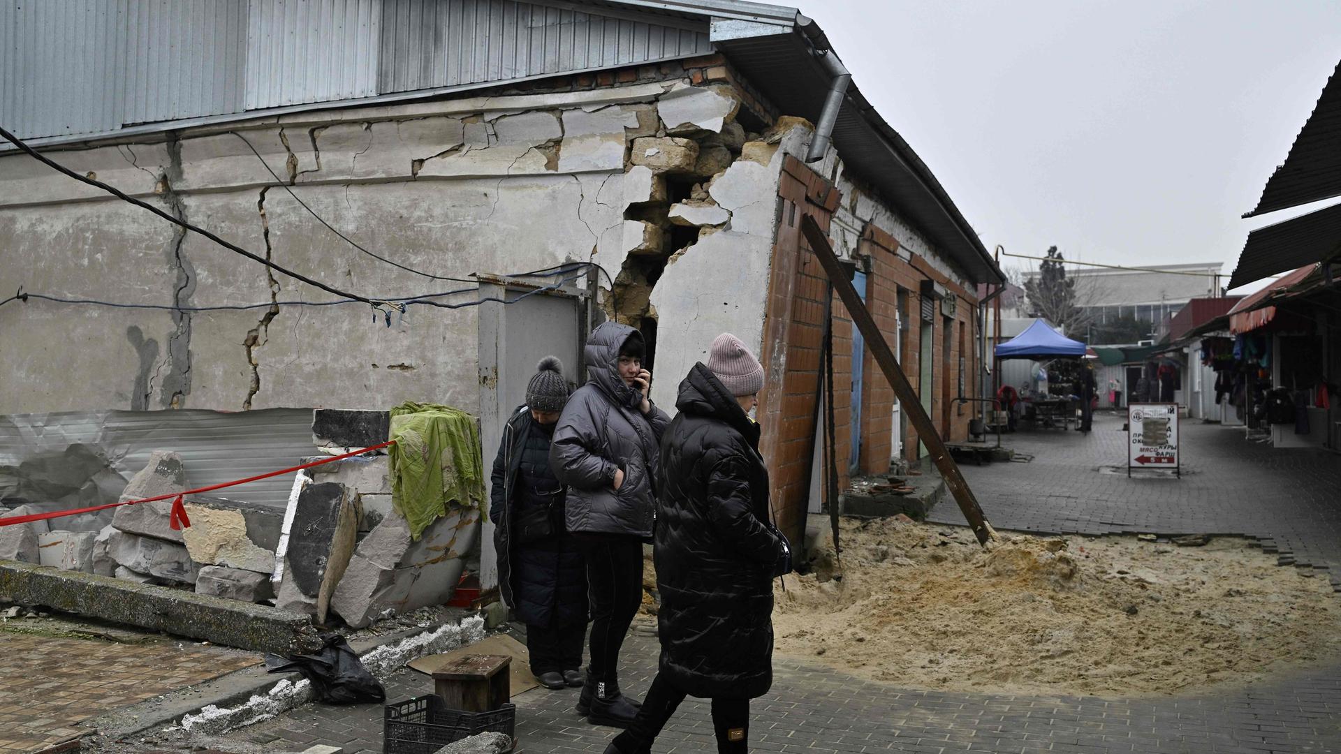 Des vendeurs se tiennent à côté d'un bâtiment endommagé après l'attaque d'un marché dans la ville d'Ochakiv le 10 décembre 2022.