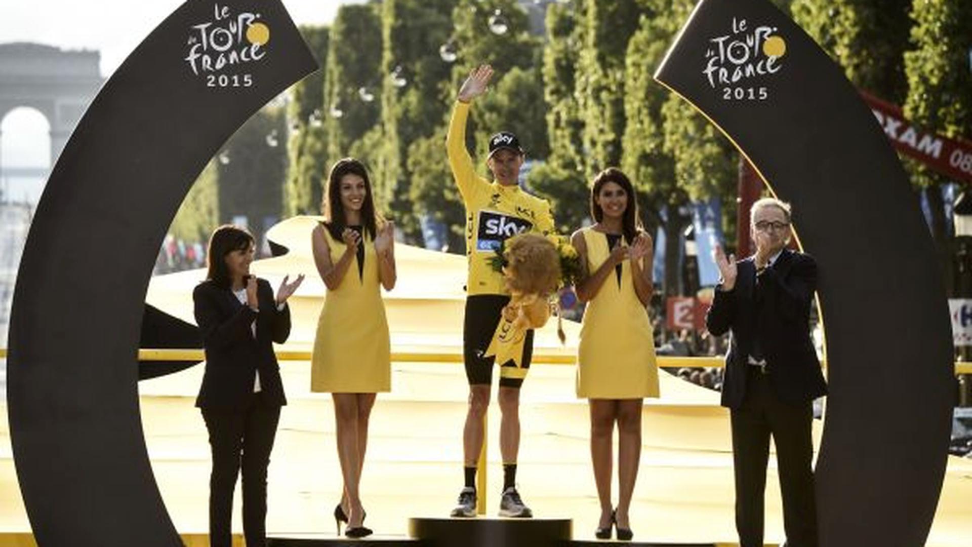 Tour de France 2015's winner Great Britain's Christopher Froome celebrates his victory on the podium on the Champs-Elysees avenue, flanked by Paris mayor Anne Hidalgo (L) at the end of the 109,5 km twenty-first and last stage of the 102nd edition of the Tour de France cycling race on July 26, 2015, between Sevres and Paris. AFP PHOTO / ERIC FEFERBERG