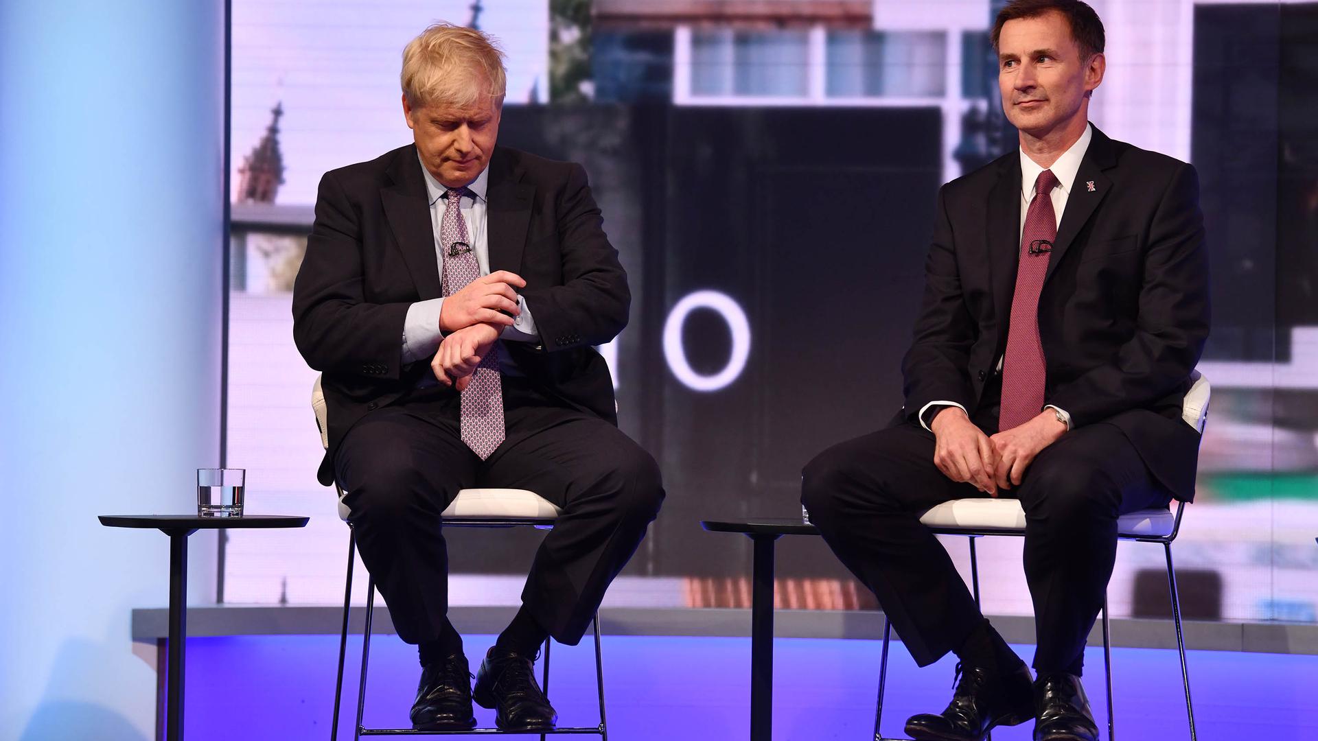 In a handout picture released by the British Broadcasting Corperation (BBC) on June 18, 2019 Conservative Party leadership contender Conservative MP Boris Johnson (L) checks his watch seated next to Britain's Foreign Secretary Jeremy Hunt (R) during a BBC television leadership debate in London on June 18, 2019. - The UK leadership race narrowed to five in a second vote by MPs on June 18 with the remaining contenders taking part in a televised debate organised by the BBC. (Photo by JEFF OVERS / BBC / AFP) / RESTRICTED TO EDITORIAL USE - MANDATORY CREDIT " AFP PHOTO / JEFF OVERS-BBC " - NO MARKETING NO ADVERTISING CAMPAIGNS - DISTRIBUTED AS A SERVICE TO CLIENTS TO REPORT ON THE BBC PROGRAMME OR EVENT SPECIFIED IN THE CAPTION - NO ARCHIVE - NO USE AFTER  JULY 9, 2019 / 