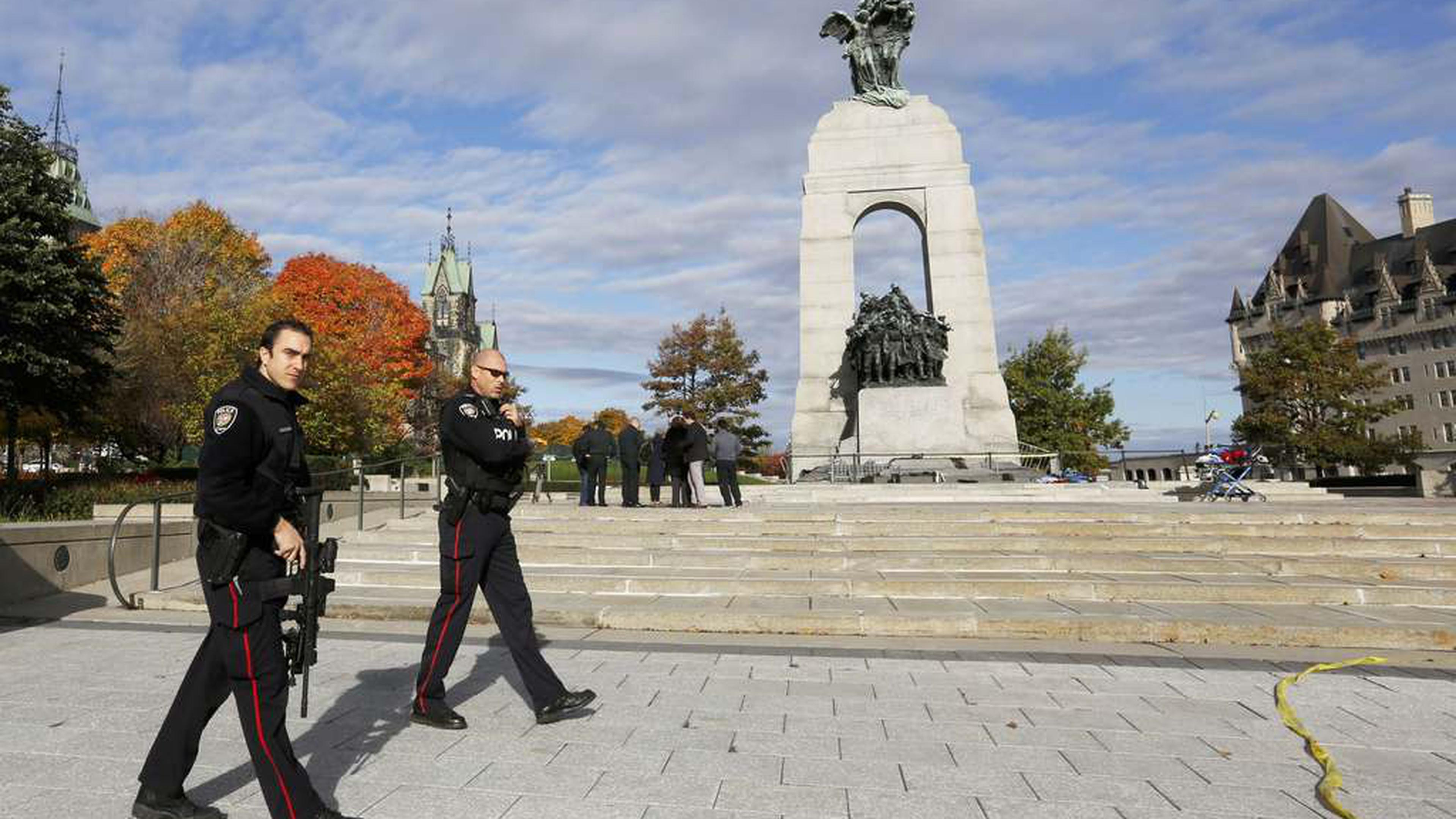 Police officers patrol alongside the Canadian War Memorial following a shooting incident in Ottawa October 22, 2014.  A Canadian soldier was shot at the Canadian War Memorial and a shooter was seen running towards the nearby parliament buildings, where more shots were fired, according to media and eyewitness reports.  REUTERS/Chris Wattie (CANADA  - Tags: POLITICS CRIME LAW)