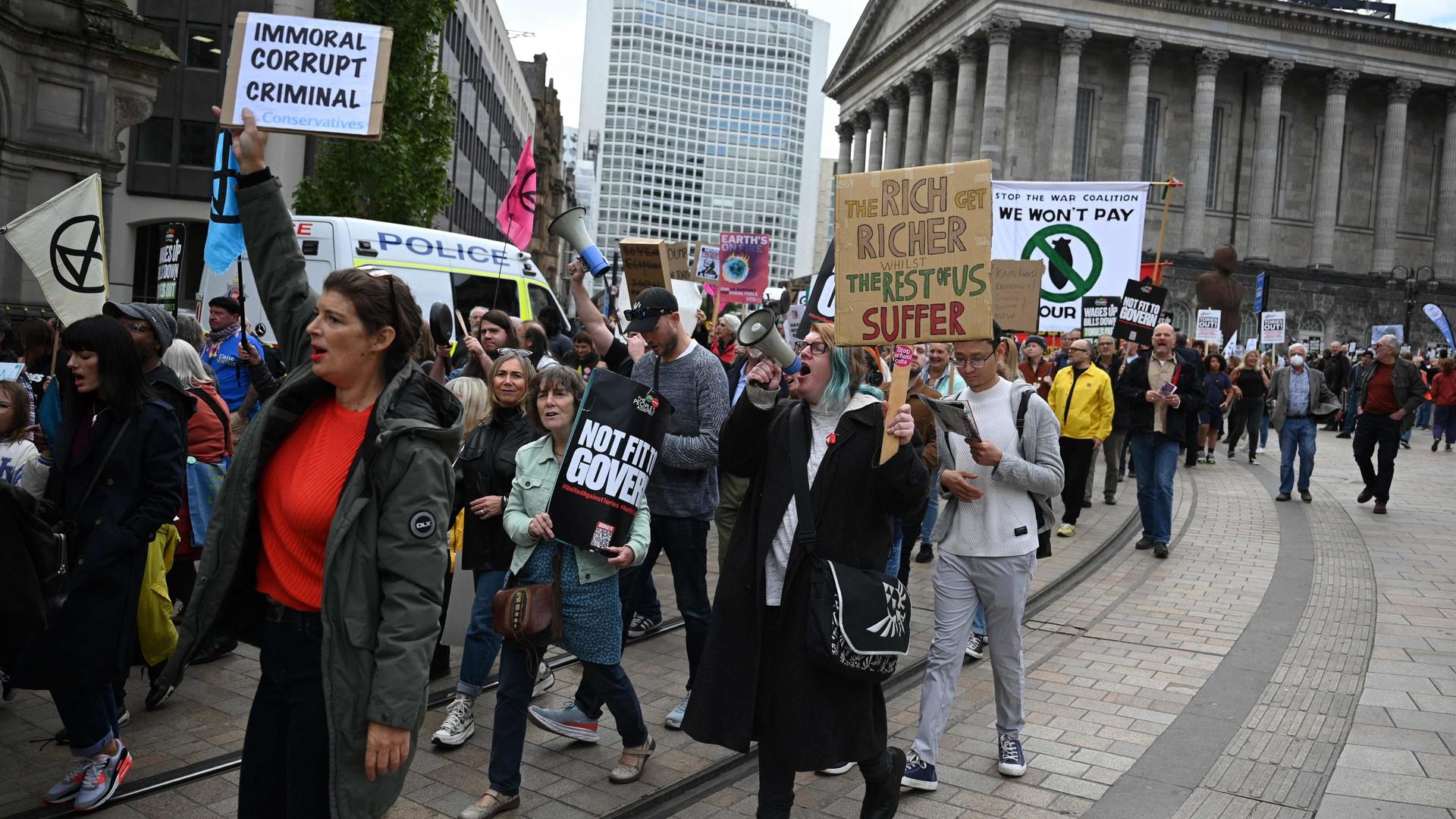 Des manifestants ont brandi des pancartes lors d'une manifestation antigouvernementale sur la place Victoria le jour de l'ouverture de la conférence annuelle du parti conservateur à Birmingham.