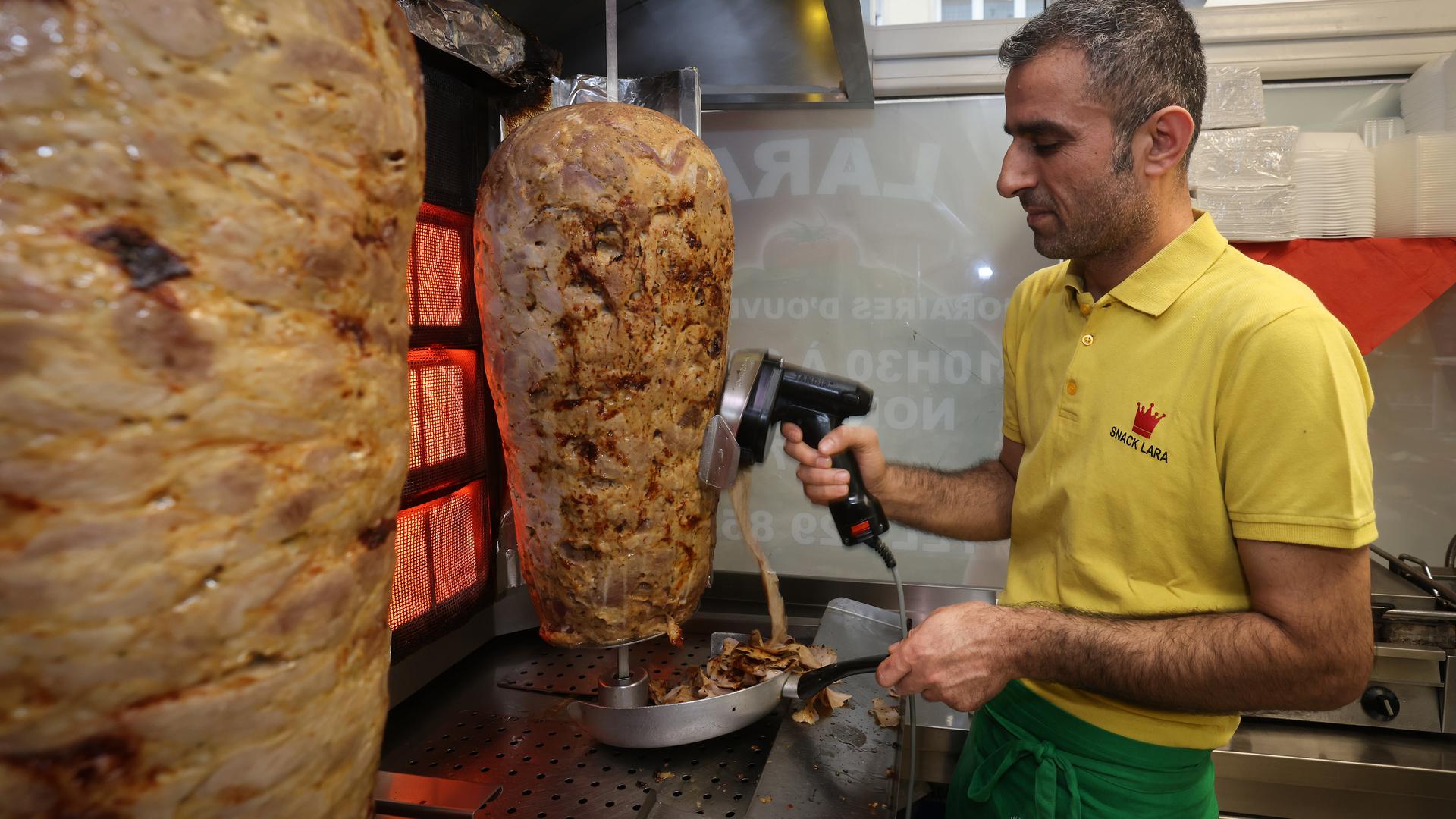 Mehmet Korkmaz coupe la viande du kebab au Snack Lara.