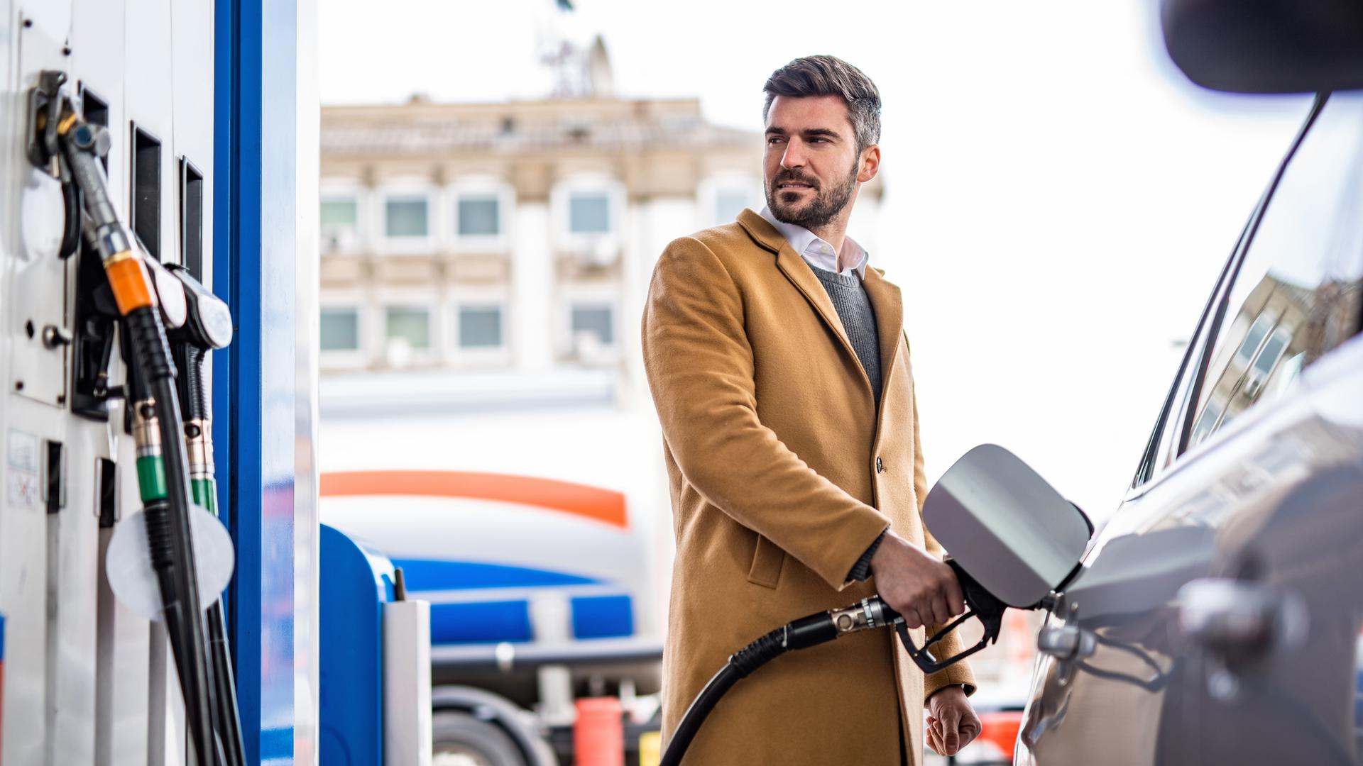 Elegant man refueling his car's tank at the gas station in the city.