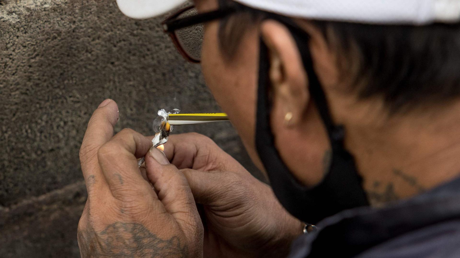 In this photo taken on January 12, 2021 motorbike taxi driver Soonthorn poses for photos as smokes a methamphetamine yaba pill to demonstrate how he consumes the drug during an interview with AFP in Bangkok. - Thailand has long been a global gateway for exports of the drug but the coronavirus pandemic's sudden disruption of international transport has seen a surge in cut-price "yaba" tablets in the local market. (Photo by Jack TAYLOR / AFP) / To go with 'THAILAND-CRIME-DRUGS-HEALTH,FOCUS' by Lisa MARTIN and Pitcha DANGPRASITH